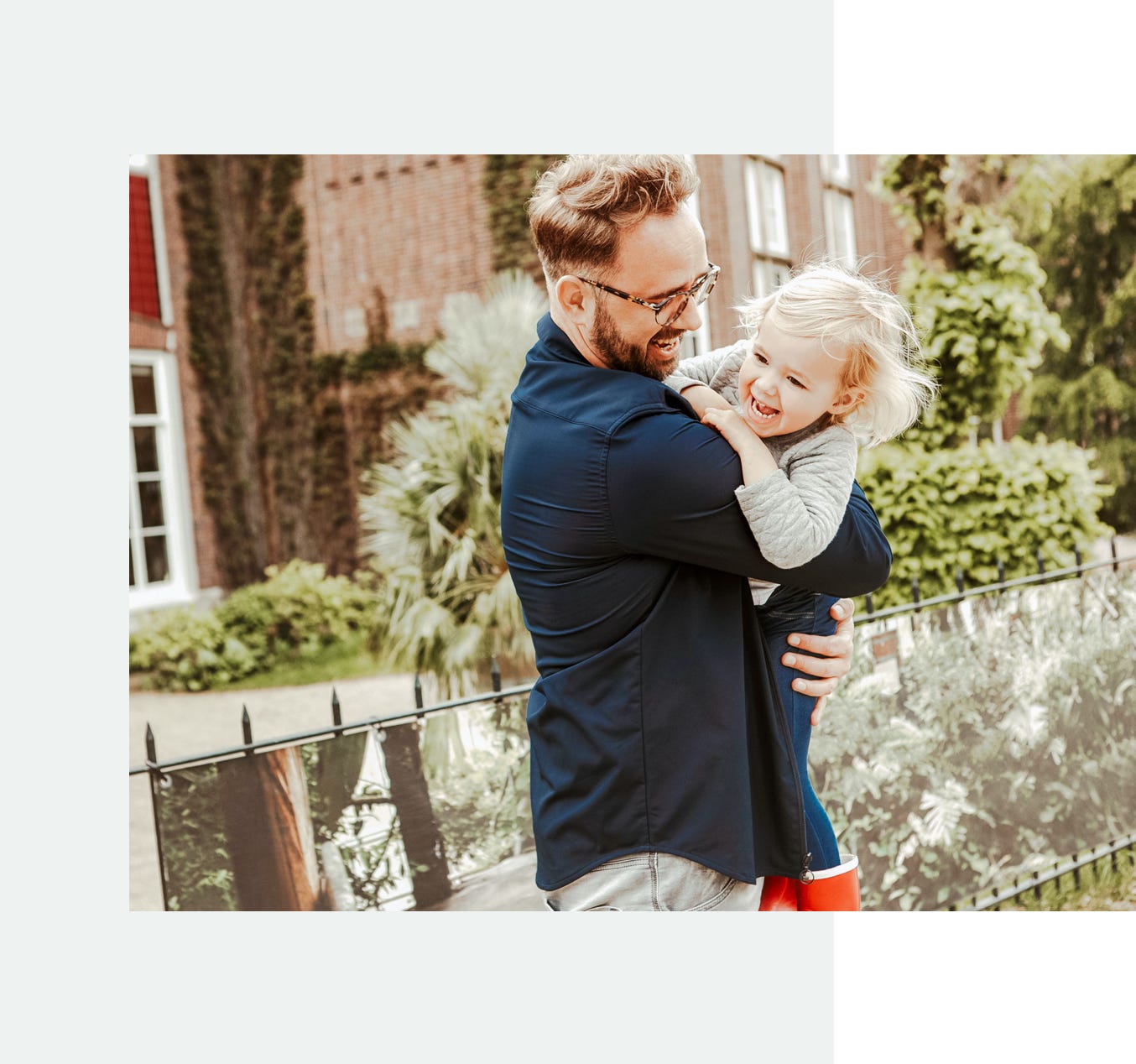 Laughing father picking up a happy daughter outside in garden