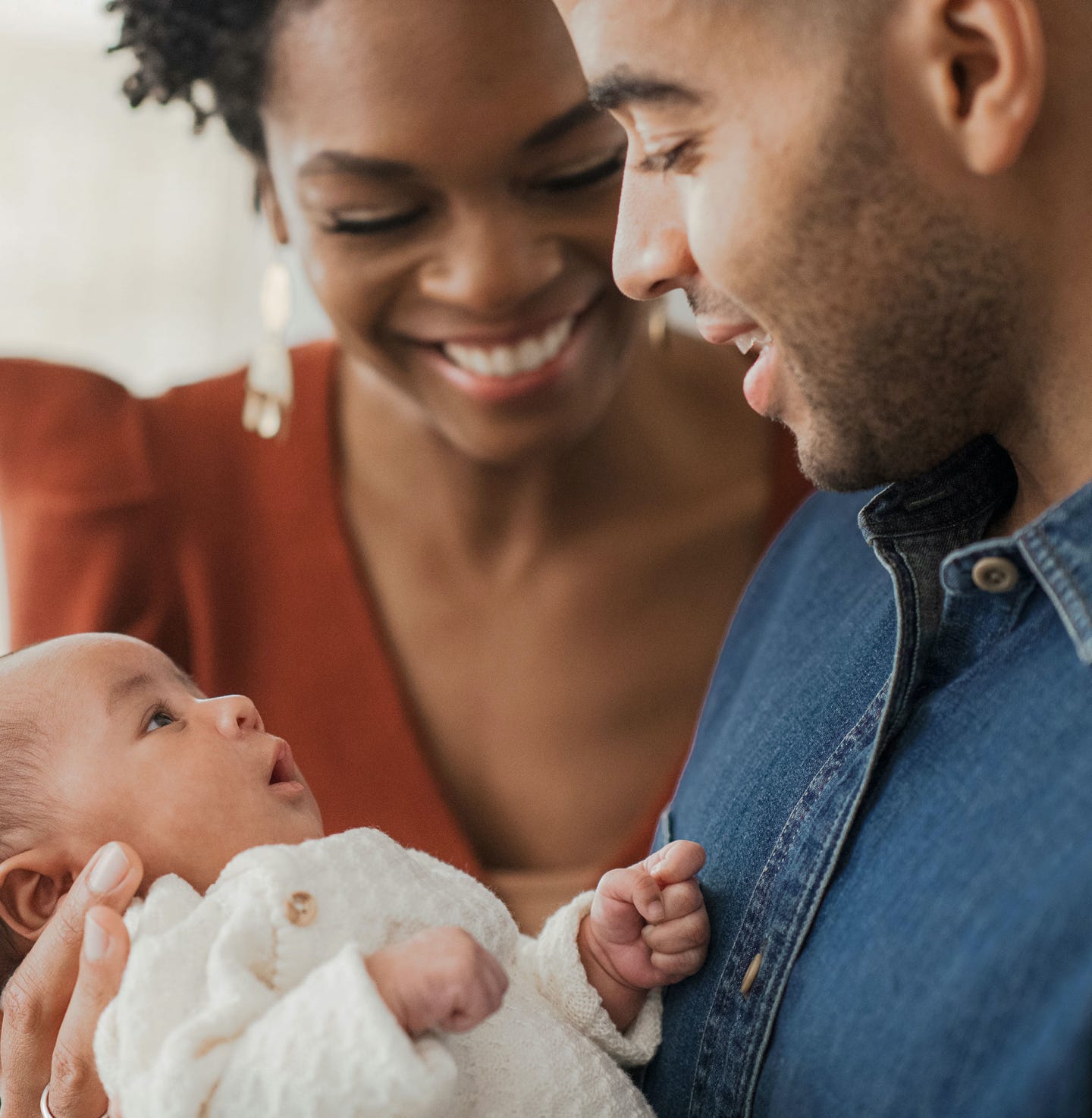 Smiling mother and father looking at and holding a happy newborn baby